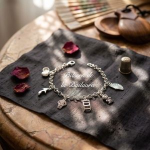 Vista principal de la Pulsera de Plata Bailaora sobre tela negra junto a abanico, castañuelas y pétalos en mesa de mármol.